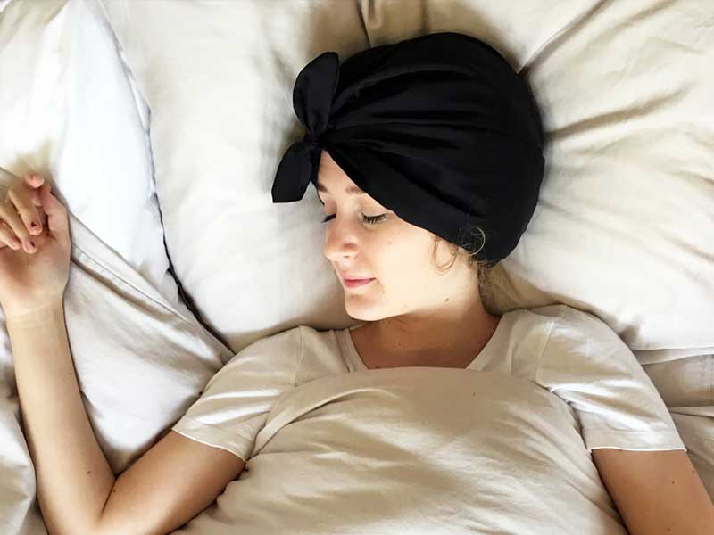 Relaxing woman sleeping comfortably in bed with a black turban, lifestyle, wellness, stay in Bangkok, serenity, rest, comfort, tourism, travel destinations.