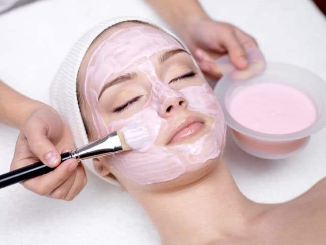 Gentle facial treatment with pink clay mask in luxury spa setting.