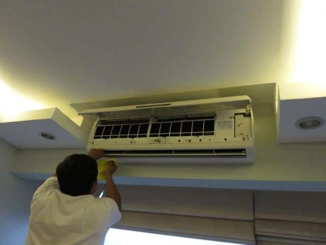 Cleaning air conditioner unit in modern hotel room.